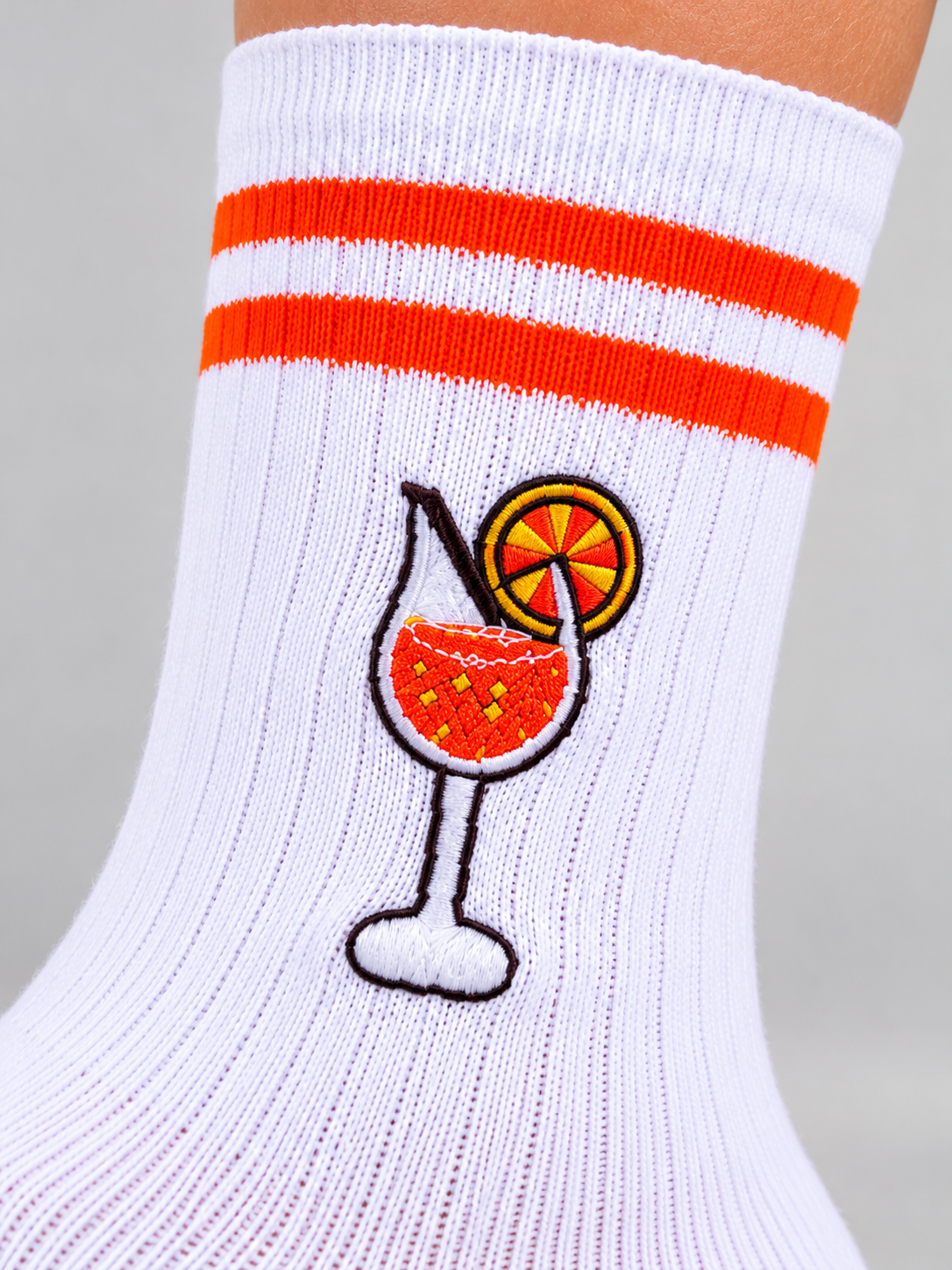 Gesticktes Cocktailglas mit Orangenscheibe auf weißer Socke, Nahaufnahme