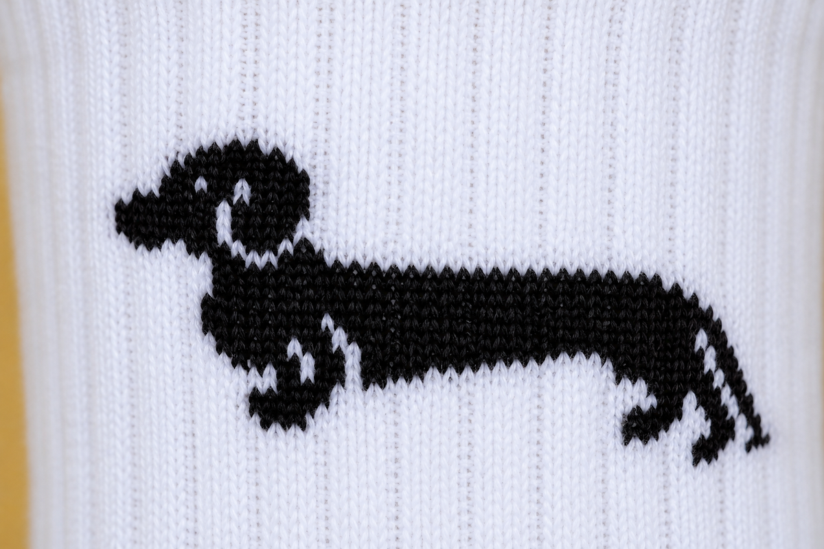 Schwarzes Dackel-Motiv auf weißer Socke, Nahaufnahme der Stickerei