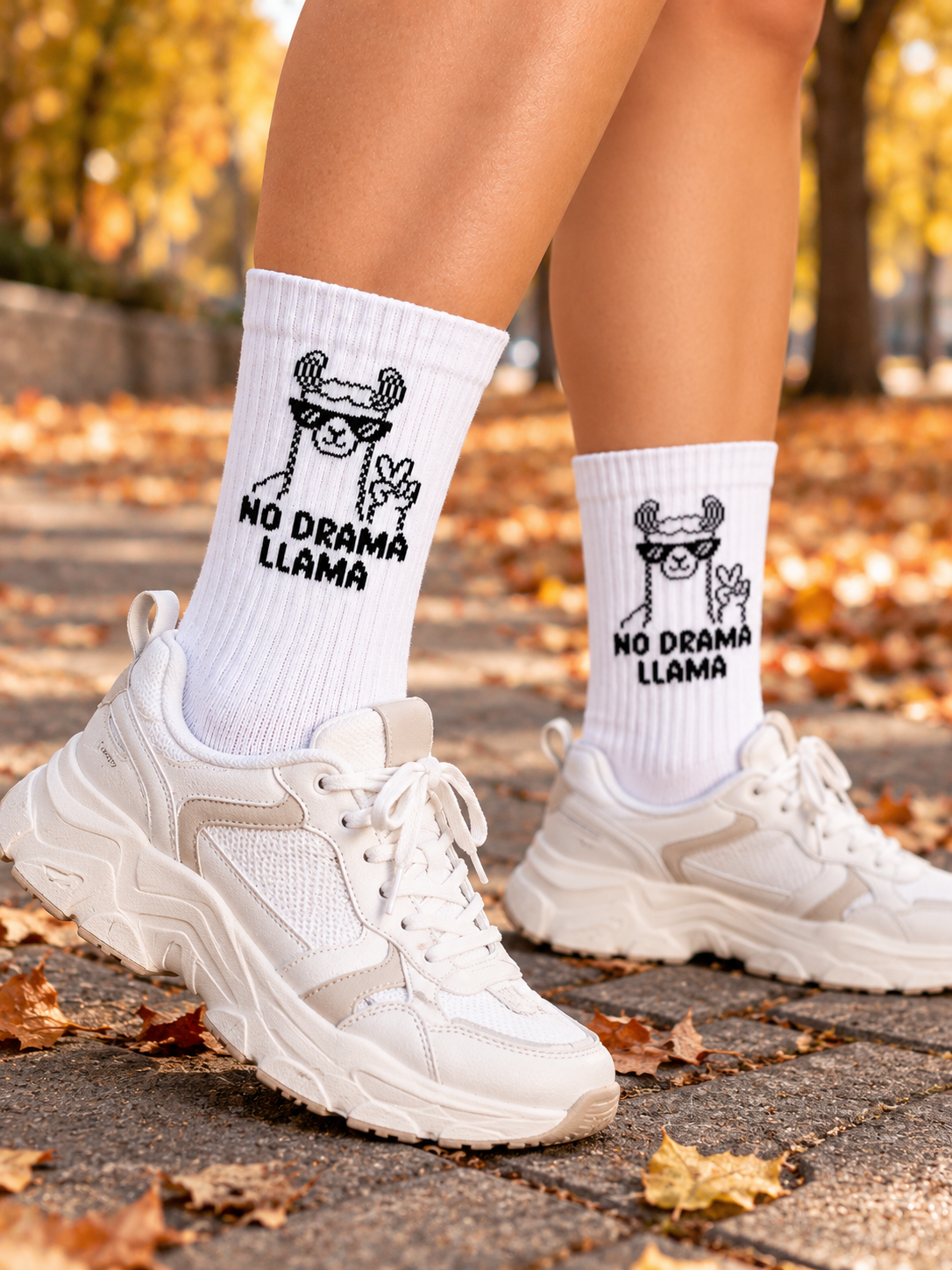 Llama Socken in Weiß, getragen zu hellen Sneakern im Herbstlaub